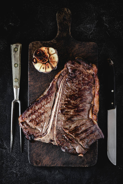 Trocken gegrilltes T-Bone Steak auf rustikalem Schneidebrett. usda prime beef. - Foto, Bild