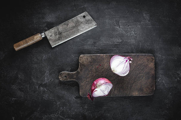 Tagliere e cipolla rossa dimezzata con mannaia di carne
 - Foto, immagini