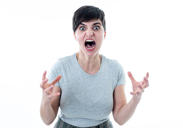 Close up portrait of Young attractive caucasian woman with an angry face. Looking mad and crazy shouting and making furious gestures. Isolated on white background. Facial expressions and emotions. - Zdjęcie, obraz