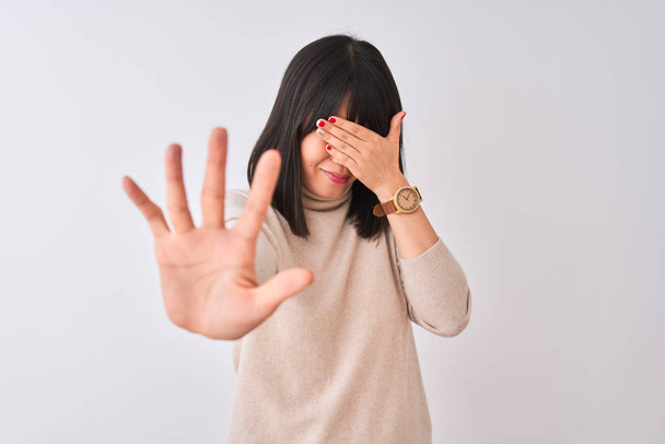 Young beautiful chinese woman wearing turtleneck sweater over isolated white background covering eyes with hands and doing stop gesture with sad and fear expression. Embarrassed and negative concept. - Fotó, kép