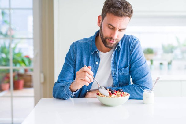 Pohledný muž snídani doma jíst obiloviny a usmívá se - Fotografie, Obrázek