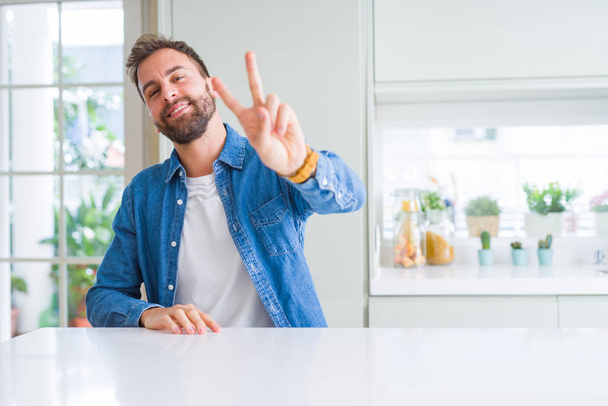 Handsome man at home smiling looking to the camera showing fingers doing victory sign. Number two. - Foto, Bild