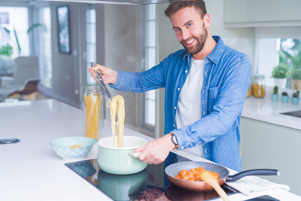 Handsome man cooking pasta at home - Foto, imagen