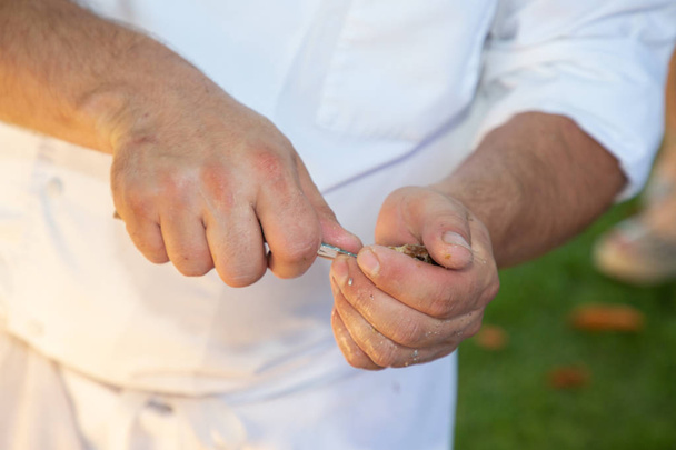 Mann öffnet rohe Auster mit Messer - Foto, Bild