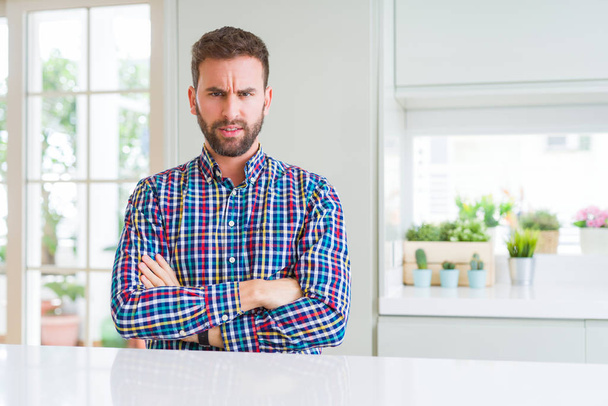 Handsome man wearing colorful shirt skeptic and nervous, disapproving expression on face with crossed arms. Negative person. - Фото, изображение