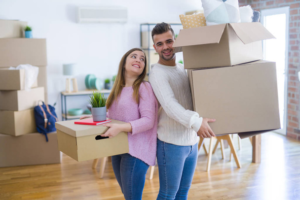 Молода красива пара закохалася в переїзд в новий будинок, тримаючи картонні коробки дуже щасливими і веселими для нової квартири
 - Фото, зображення
