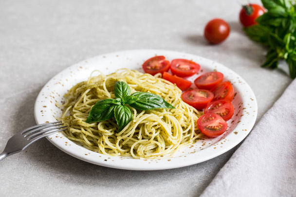 Spaghetti con salsa di pesto fatta in casa, foglie di basilico e pomodori /
 - Foto, immagini