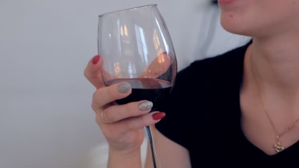Woman with a glass of red wine in her hands drinks wine. - Záběry, video