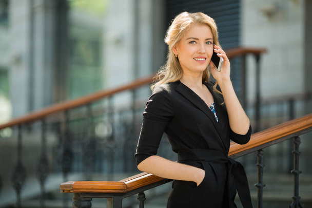 beautiful young woman in a black suit talking on the phone - Photo, Image