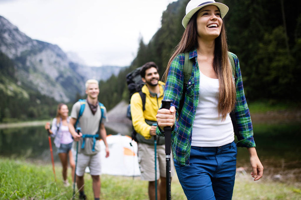 Adventure, travel, tourism, hike and people concept. Smiling friends walking with backpacks over natural background - Φωτογραφία, εικόνα