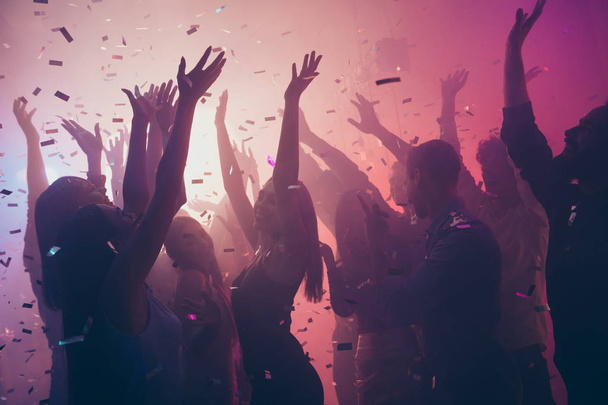 Photo of many birthday event people dancing colorful lights confetti flying enjoy nightclub hands raised up wear shiny clothes - Foto, imagen