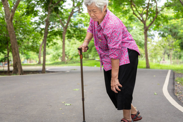 Азіатський старший жінка артрит, остеоартрит, люди похилого віку ходьба з Ходунки у відкритому парку, тримаючись рукою на коліна, відчуваючи біль в коліні, опухлими коліна, біль у ногах, медична та охорона здоров'я концепція - Фото, зображення