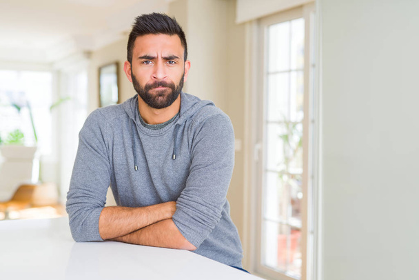 Handsome hispanic man wearing casual sweatshirt at home skeptic and nervous, disapproving expression on face with crossed arms. Negative person. - Foto, Bild
