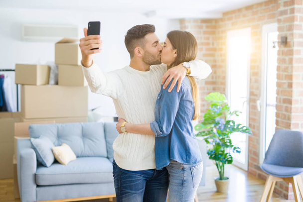 Hermosa pareja tomando una foto selfie usando un teléfono inteligente en un nuevo
 - Foto, Imagen