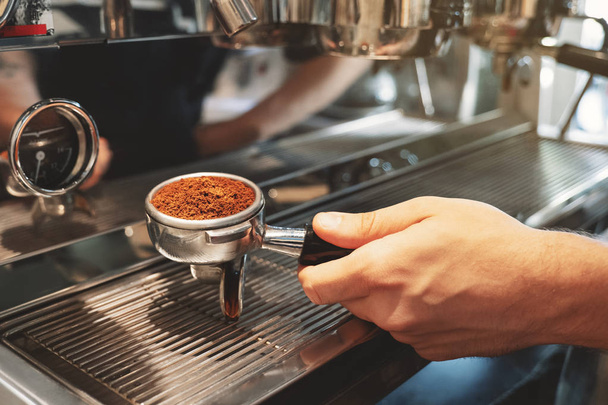 barista holding coffee holder with ground coffee near professional coffee machine preparing espresso in cafe close up - Foto, immagini