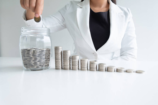 жінка рука кладе монету в скляний пляшковий банк з графом монет, збільшуючи бізнес до успіху та заощаджуючи на концепції пенсії
 - Фото, зображення
