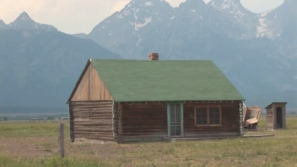 Close of old cabin, shot then zooms out withe the Tetons near Grand Teton National Park - Footage, Video