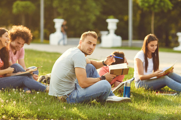 A group of students studying books sitting in a city park. - Foto, afbeelding