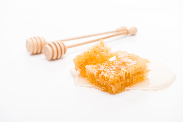Honingraat met honing en houten honing dippers op witte achtergrond - Foto, afbeelding