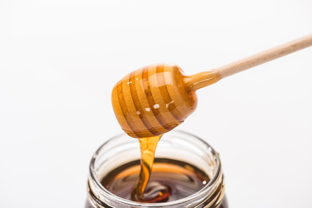 pot met honing en houten honing Dipper geïsoleerd op wit  - Foto, afbeelding
