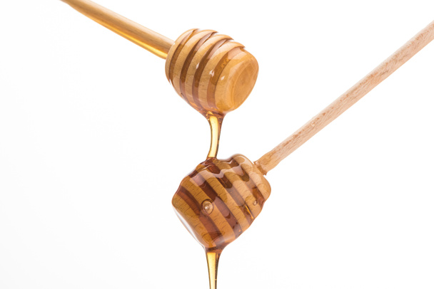 wooden honey dippers with dripping sweet honey isolated on white  - Foto, Imagem