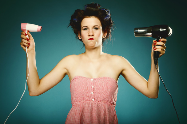 Funny girl in curlers with hairdryer styling hair - Photo, Image