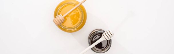 panoramic shot of jars with honey and honey dippers on white background - Photo, Image