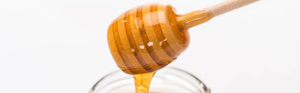 panoramic shot of wooden honey dipper with dripping delicious honey isolated on white - Foto, immagini