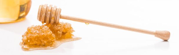 甘い蜂蜜と木製の蜂蜜ディッパーと白で隔離された瓶の近くにハニカムのパノラマショット - 写真・画像