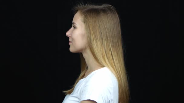 Vue rapprochée du profil de heureuse jeune femme blonde caucasienne souriante. Portrait femelle sur fond noir
.  - Séquence, vidéo