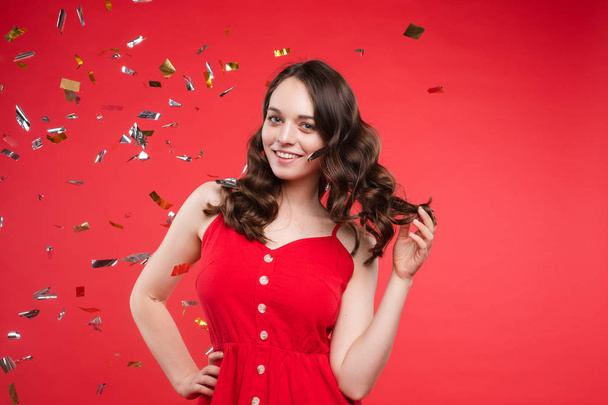 Gorgeous brunette girl in red dress in confetti. - Foto, Imagem