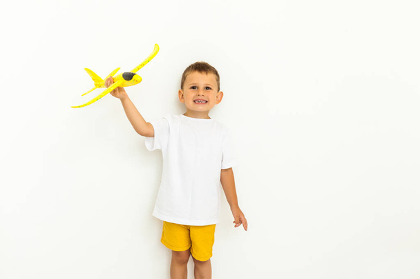 fröhliches Kleinkind spielt mit gelbem Spielzeugflugzeug - Foto, Bild