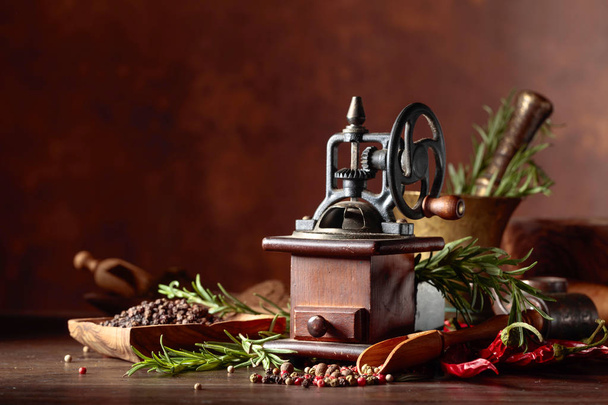 Moinho de pimenta vintage com utensílios de cozinha, especiarias e alecrim
 - Foto, Imagem