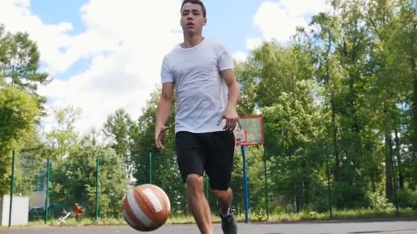 Young man playing basketball outdoors with friend and dribbling - Video
