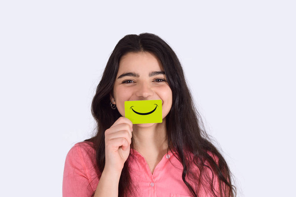 Young woman holding smile paper on studio. - Zdjęcie, obraz