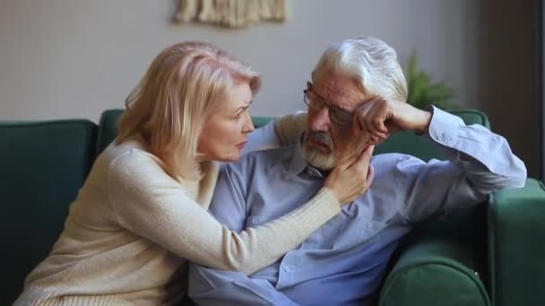 Caring aged wife comforting talking to upset elderly husband - Materiaali, video