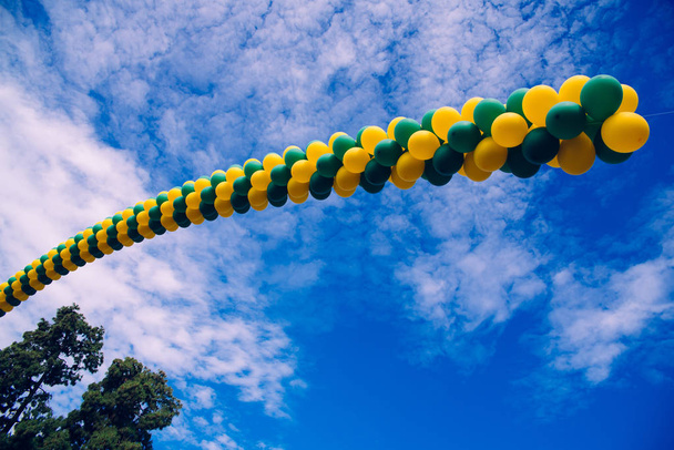 Ряд різнокольорових кульок, що перетинають блакитне небо з хмарами, назад
 - Фото, зображення