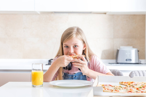 маленькая девочка ест пиццу сидя за столом
 - Фото, изображение
