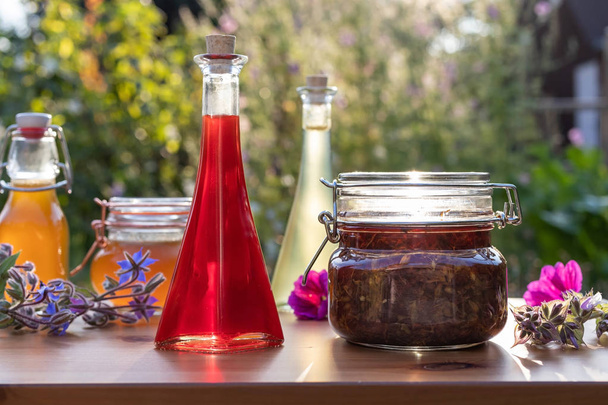 Bottles of homemade herbal oils and syrups in garden - Photo, Image