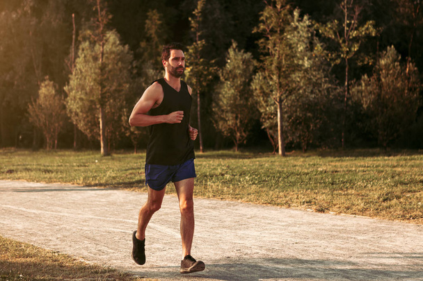a male sportive person running outdoors in a park. healthy lifestyle concept - Photo, Image