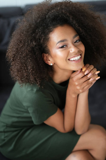 Nice afro-amercian woman with curly hair is chilling on the sofa. - Foto, Bild