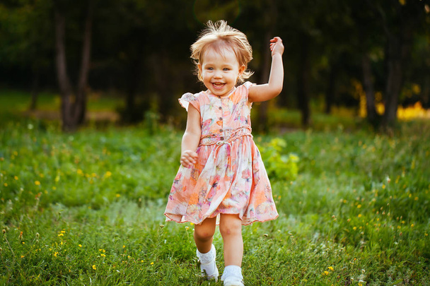 Feliz niña linda corriendo sobre el césped en el parque. Felicidad
 - Foto, imagen