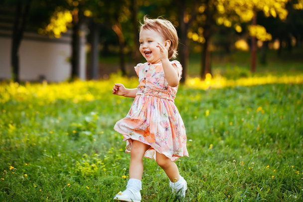 Joyeux petite fille mignonne courant sur l'herbe dans le parc. Le bonheur
 - Photo, image