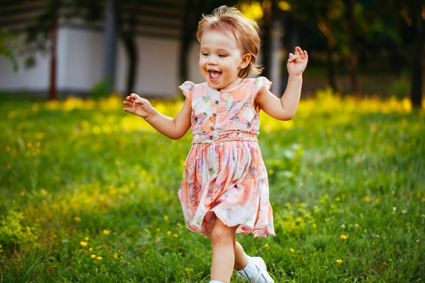 Happy cute little girl running on the grass in the park. Happiness - Фото, зображення
