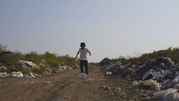 Chico pateando plástico lata en volcado
 - Foto, imagen