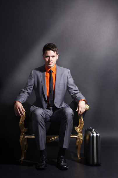 A man is sitting in a golden chair - Photo, Image