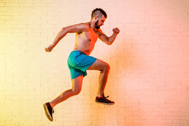 Young sporty man performs a jump on a yellow background. - Fotografie, Obrázek