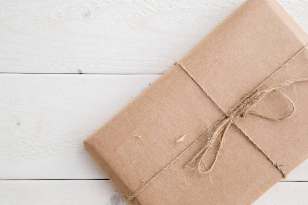 посылка, подарок упакован в экологически чистую бумагу на светлом деревянном бэкгро
 - Фото, изображение