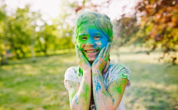 Portrait of a cute girl painted in the colors of Holi festival. - Valokuva, kuva
