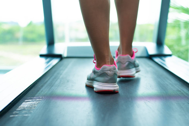 Cierre las piernas de las mujeres en zapatillas de deporte de color rosa en una. Cinta de correr en el gimnasio
 - Foto, imagen